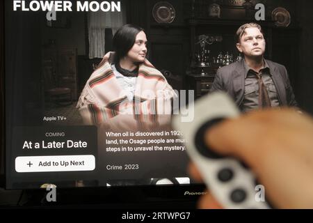 Apple TV plus App auf einem tv-Bildschirm, der die bevorstehenden Filmkillerer des Blumenmondes mit dem Schatten einer Person hervorhebt, die eine Siri-Fernbedienung hält Stockfoto