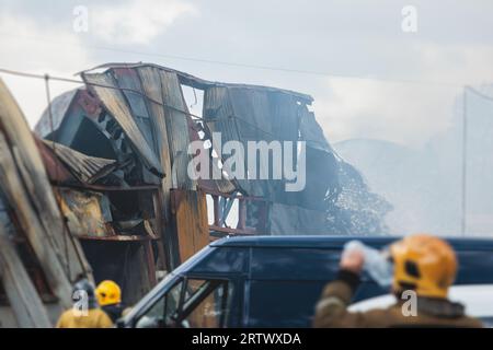 Massive Großbrände in der Stadt, brennende Lagerfabrik, Lagergebäude brennt, Feuerwehrteam, Feuerwehrleute im Dienst, Stockfoto