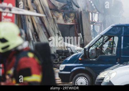 Massive Großbrände in der Stadt, brennende Lagerfabrik, Lagergebäude brennt, Feuerwehrteam, Feuerwehrleute im Dienst, Stockfoto