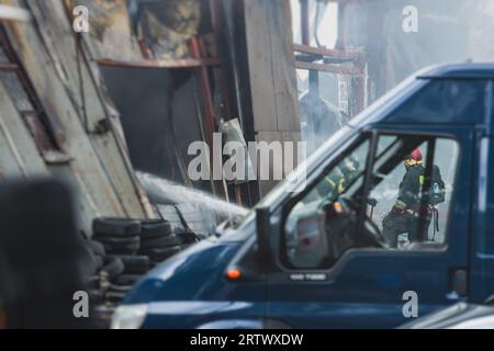 Massive Großbrände in der Stadt, brennende Lagerfabrik, Lagergebäude brennt, Feuerwehrteam, Feuerwehrleute im Dienst, Stockfoto