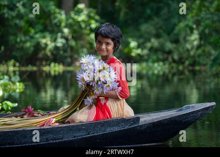 Ein Mädchen aus Bangladesch hält eine Menge Seerosen, die in Ujirpur in Barisal aus einem großen Wasserkörper namens Shatla Beel stammen. Bangladesch. Stockfoto