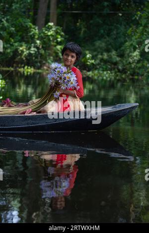 Ein Mädchen aus Bangladesch hält eine Menge Seerosen, die in Ujirpur in Barisal aus einem großen Wasserkörper namens Shatla Beel stammen. Bangladesch. Stockfoto