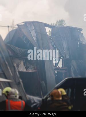 Massive Großbrände in der Stadt, brennende Lagerfabrik, Lagergebäude brennt, Feuerwehrteam, Feuerwehrleute im Dienst, Stockfoto