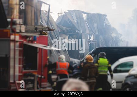 Massive Großbrände in der Stadt, brennende Lagerfabrik, Lagergebäude brennt, Feuerwehrteam, Feuerwehrleute im Dienst, Stockfoto