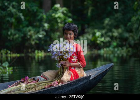 Ein Mädchen aus Bangladesch hält eine Menge Seerosen, die in Ujirpur in Barisal aus einem großen Wasserkörper namens Shatla Beel stammen. Bangladesch. Stockfoto