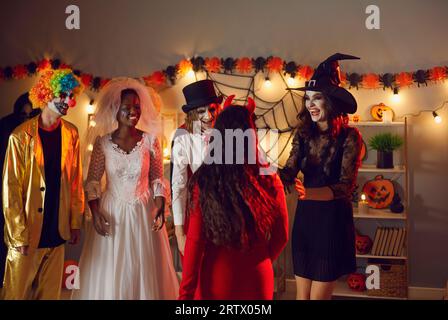 Eine Gruppe von Freunden in verschiedenen gruseligen Kostümen hat Spaß, auf der Halloween-Party miteinander zu sprechen. Stockfoto