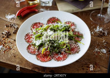 Rindfleisch-Carpaccio. Borettane-Zwiebeln, sonnengetrocknete Tomaten, Trüffeldressing, Rucola-Salat, Parmesankäse. Traditionelle italienische Antipasti-Snacks serviert Stockfoto
