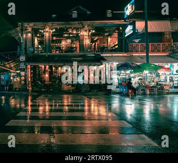 Eine nasse Nacht bringt die Farbe in den Straßen von Siem Reap zum Ausdruck. Die Lichter von Bars und Restaurants spiegeln sich auf den Straßen wider. Ein Fußgängerkreuz Stockfoto