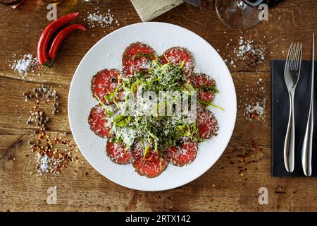 Rindfleisch-Carpaccio. Borettane-Zwiebeln, sonnengetrocknete Tomaten, Trüffeldressing, Rucola-Salat, Parmesankäse. Traditionelle italienische Antipasti-Snacks serviert Stockfoto