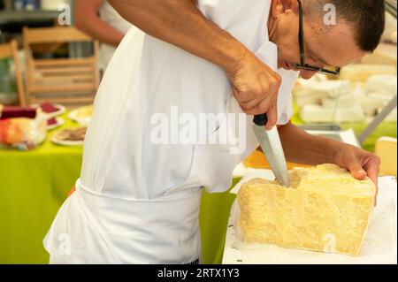 Bra (Cuneo), Italien. September 2023. Einweihung der XIV. Ausgabe der internationalen Käsemesse, organisiert von der Slow Food-Bewegung und der Stadtverwaltung von Bra. Auf diesem Bild sieht man einen Verkäufer, der einen regionalen italienischen Käse schneidet, der mit umweltfreundlichen Methoden hergestellt wird. Quelle: Luca Prestia / Alamy Live News Stockfoto