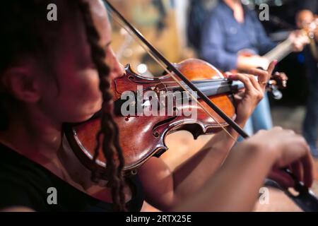 Eine Geigerin spielt Geige. Die Band spielt auf der Bühne, Rockmusik-Konzert. Stockfoto