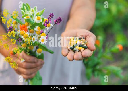 Eine alte Frau hält Nahrungsergänzungsmittel mit Heilkräutern und Blumen in den Händen. Selektiver Fokus. Natur. Stockfoto