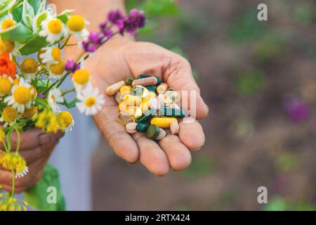 Eine alte Frau hält Nahrungsergänzungsmittel mit Heilkräutern und Blumen in den Händen. Selektiver Fokus. Natur. Stockfoto