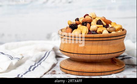 Gemischte Nüsse in Holzschale. Nüsse auf weißem Holzgrund. Gemischte Nüsse, zubereitet mit Haselnüssen, Mandeln, Cashews, Pistazien, Pistazien und Trauben. Kopieren Stockfoto