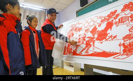 LUANNAN COUNTY, China - 10. Dezember 2021: Grundschüler lernen traditionelle chinesische Papierschneidekunst unter der Leitung von Lehrern, Nord-C Stockfoto