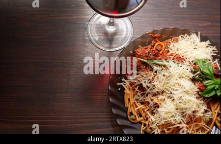 Köstliche Spaghetti Bolognese und ein Glas Rotwein auf einem Holztisch Stockfoto