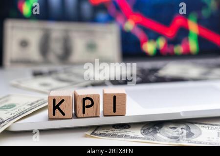 Leistungskennzahlen. KPI das Wort auf Holzwürfeln, Würfel stehen auf einer reflektierenden Oberfläche, im Hintergrund ist ein Geschäftsdiagramm. Business und Stockfoto