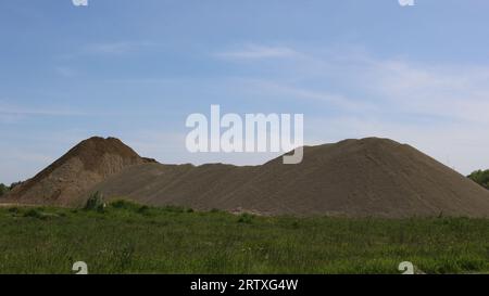 Hügel aus abgerundeten Steinen auf einer Kiesgrube, Ausgrabung von Mineralien und Gestein aus dem Boden im industriellen Maßstab, ein Haufen großer Pflastersteine Stockfoto