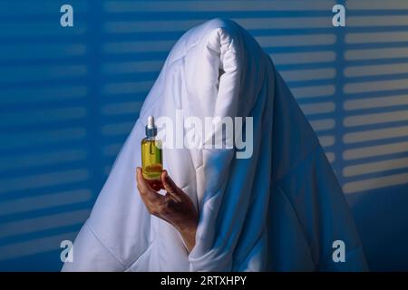 Looking Serenity: Mädchen bekämpft Schlaflosigkeit unter seiner treuen Decke mit Schlaföl. Stockfoto