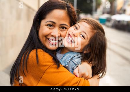 Glückliche südostasiatische Mutter mit ihrer Tochter, die Spaß im Stadtzentrum hat - nette Familie draußen Stockfoto