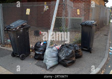 Slough, Berkshire, Großbritannien. September 2023. Der Slough Borough Council hat eine Änderung der Müllablagen der Bewohner eingeführt, um die Bewohner zu ermutigen, mehr recycelt zu werden. Graue Abfallbehälter mit allgemeinen Abfällen, einschließlich Lebensmitteln, werden jetzt einmal alle 14 Tage anstatt einmal pro Woche gesammelt, wobei das Recycling in roten Abfallbehältern erfolgt, die in der zweiten Woche gesammelt werden. Dies führt zu überfüllten Mülltonnen und verstreuten Straßen im Stadtzentrum von Slough. Kredit: Maureen McLean/Alamy Stockfoto