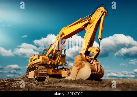 Großer Bagger auf der Baustelle an einem sonnigen Tag mit blauem Himmel und flauschigen Wolken, cooles modernes Aussehen Stockfoto