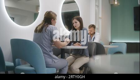 Die Ärztin sitzt mit dem Patienten im Klinikcafé. Fachärztin diskutiert mit Frau medizinisch-diagnostische Ergebnisse. Digitales Tablet mit MRT- oder CT-Bild des Gehirns. Krankenhaus oder medizinisches Zentrum Cafeteria. Stockfoto