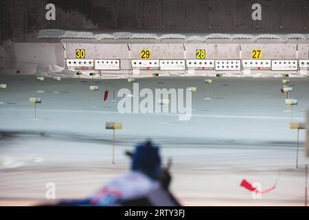 Biathlet mit Gewehr auf einem Schießstand während des Biathlontrainings, Skifahrer auf dem Trainingsgelände im Winterschnee, Athleten nehmen an Biathlonwettbewerben Teil Stockfoto