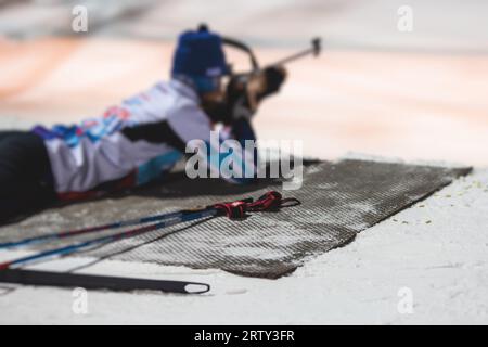 Biathlet mit Gewehr auf einem Schießstand während des Biathlontrainings, Skifahrer auf dem Trainingsgelände im Winterschnee, Athleten nehmen an Biathlonwettbewerben Teil Stockfoto