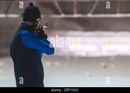 Biathlet mit Gewehr auf einem Schießstand während des Biathlontrainings, Skifahrer auf dem Trainingsgelände im Winterschnee, Athleten nehmen an Biathlonwettbewerben Teil Stockfoto