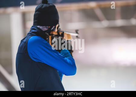 Biathlet mit Gewehr auf einem Schießstand während des Biathlontrainings, Skifahrer auf dem Trainingsgelände im Winterschnee, Athleten nehmen an Biathlonwettbewerben Teil Stockfoto