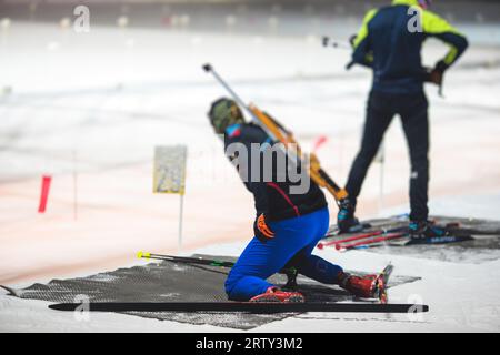 Biathlet mit Gewehr auf einem Schießstand während des Biathlontrainings, Skifahrer auf dem Trainingsgelände im Winterschnee, Athleten nehmen an Biathlonwettbewerben Teil Stockfoto