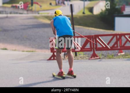 Athleten reiten Rollski auf Asphaltpiste, Gruppe Skierollen im Helm, Langlaufen mit Rollski an einem sonnigen Sommertag, Sportler Ski- Stockfoto