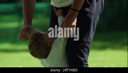 Das süße Baby lehnt sich draußen auf die Beine der Mutter. Entzückendes Kleinkind, das neben der Mutter steht und sich im Freien aufhält Stockfoto