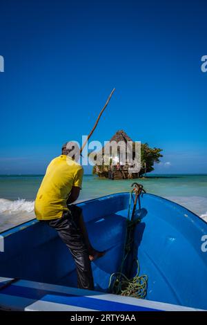 Mann auf dem Boot auf dem Weg zum HE Rock Restaurant bei Flut in Sansibar, Tansania Stockfoto