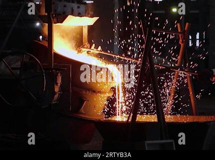 Heißes geschmolzenes Metall, das in einer metallurgischen Anlage in eine Form gegossen wird Stockfoto