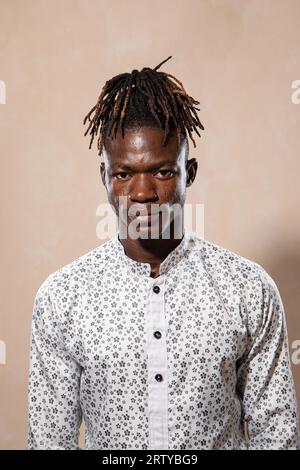 Porträt eines jungen Afrikaners mit Dreadlocks und elegant gekleidet in einem weißen Hemd. Ernsthafte Ausdrucksweise und Blick auf die Kamera Stockfoto