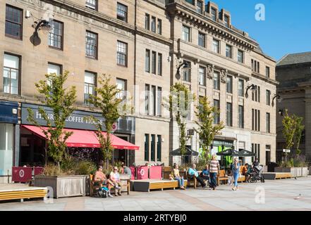 Menschen, die in der Sonne sitzen. City Square, Dundee, Schottland, Großbritannien Stockfoto