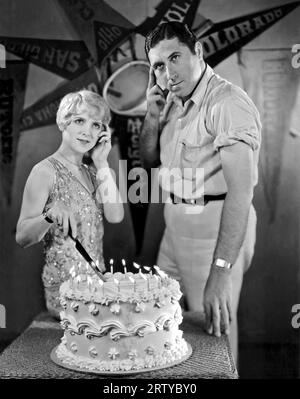 Hollywood, Kalifornien, 1927 Pauline Garon (1900–1965) und Walter lang (1896–1972) denken über ihr Motiv nach, einen Geburtstagskuchen zuzuschneiden. Stockfoto