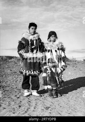 Alaska, um 1930 eine Eskimo-Familie mit Mutter, Kind und Vater, die ein Modell eines Segelschiffs in der Hand hatte. Stockfoto