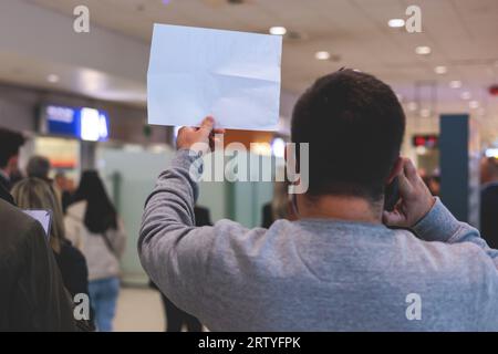 Treffen am Flughafen, Person mit einem Plakatkartenschild mit Begrüßungstext, Begrüßung des Passagiers bei der Ankunft, mit einem Namensschild zur Begrüßung von trave Stockfoto