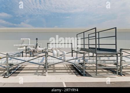 Isolierte Rohrleitungen auf dem Dach eines industriellen Kühlhauses mit Ammoniakkreislauf Zeigt eine Fußbrücke, um zu einer anderen Seite der Rohre zu gelangen. Stockfoto