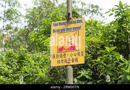 Ein Warnschild am Eingang des Zehntausend Buddhas-Klosters im Sha Tin-Bezirk warnt vor Geldspenden an gefälschte Mönche. Hongkong Stockfoto