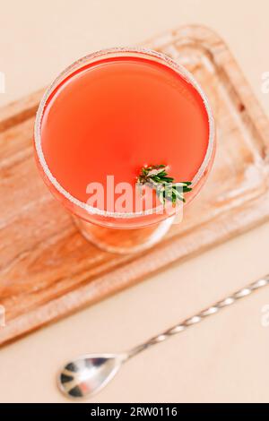 Coupé-Glas mit rotem Cocktail mit Rosmarin Stockfoto