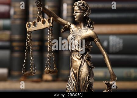 Statue von Lady Justice in der Nähe von Büchern, Nahaufnahme. Symbol der gerechten Behandlung nach dem Gesetz Stockfoto