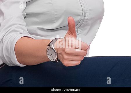 Die Hand eines Mädchens mit einer Uhr in einem weißen Hemd zeigt die Klasse mit coolen Daumen nach oben auf einem isolierten Hintergrund. Stockfoto