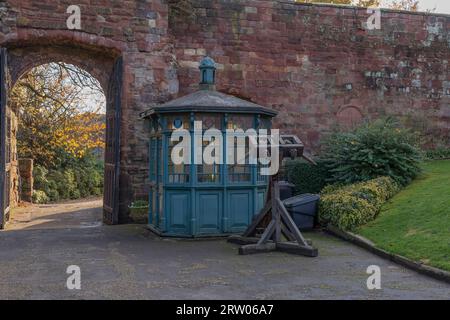 Blick durch ein altes Steintor in der Sonne mit einem alten, blau gestrichenen Holzgebäude Stockfoto