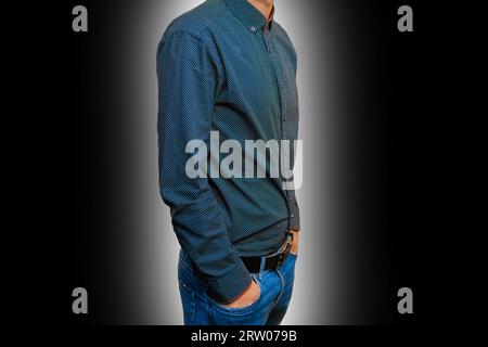 Herren Business-Mode Skinny Guy Fashion in blauem Hemd und Jeans mit Händen in der Tasche auf schwarz-weißem Hintergrund. Stockfoto