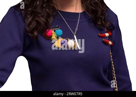 Dunkelvioletter Damen-Pullover mit farbigen Objekten, weichem Spielzeug auf einer Nadel, Nahaufnahme auf weißem isoliertem Hintergrund. Stockfoto