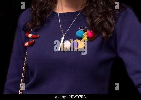 Dunkelvioletter Damen-Pullover mit farbigen Gegenständen, weichem Spielzeug auf einer Nadel, Nahaufnahme auf schwarzem Hintergrund. Stockfoto